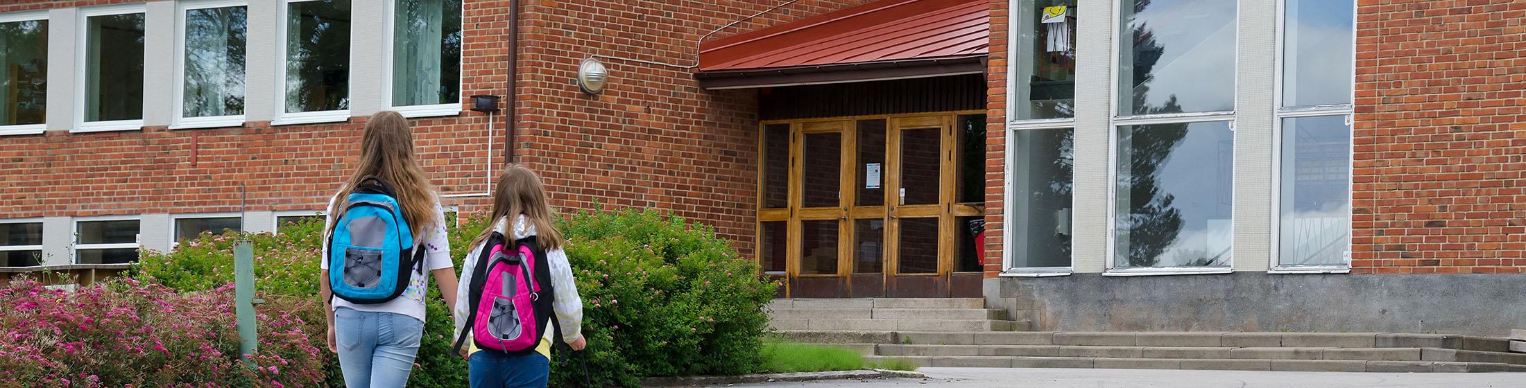 Two children entering school building